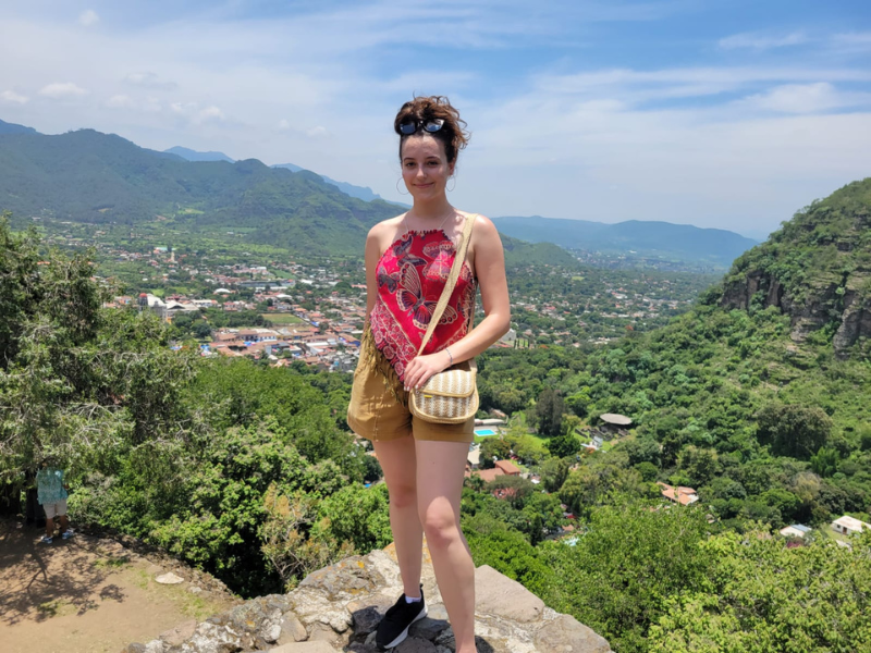 Jazzy Engle Scholar Spotlight: Jazzy stands on a rock overlooking a valley with trees and buildings