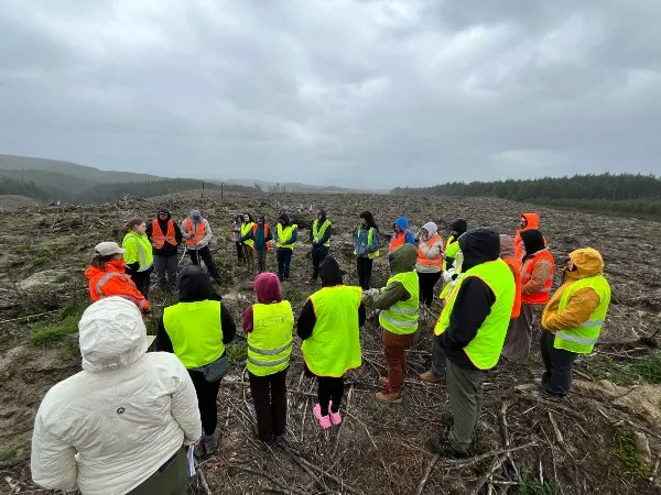 Students stand amidst cleared land.
