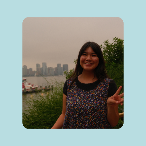 CJ Chavez poses with a peace sign in front of a cityscape.